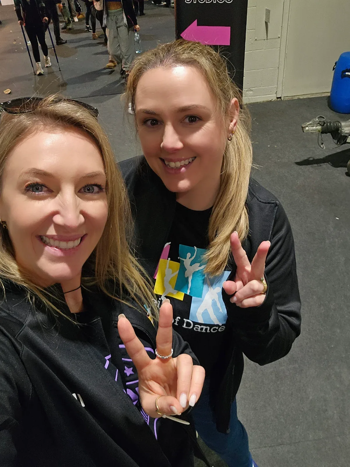 Two women in school of dance tops making hand signs